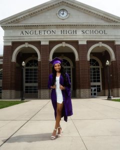 Mya Nicole smiling in her graduation dress at Angleton High School.