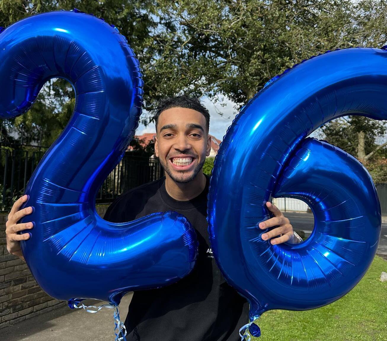 Niko Omilana holding 26-shaped balloons on his 26th birthday.