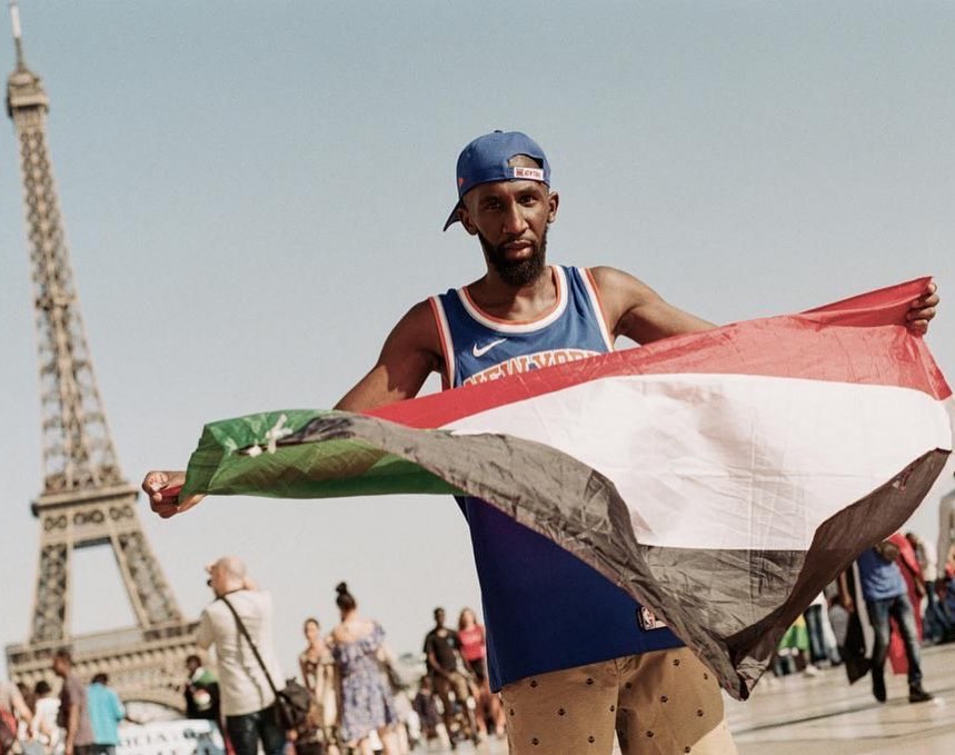 Specs Gonzalez holding a flag and smiling